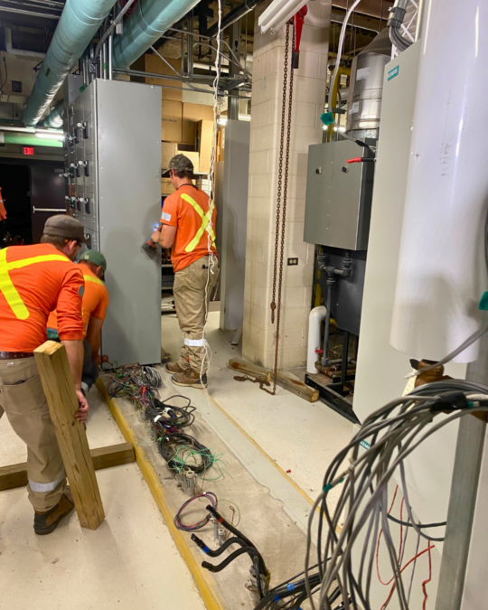 Electrical Services workers replace a motor control centre.